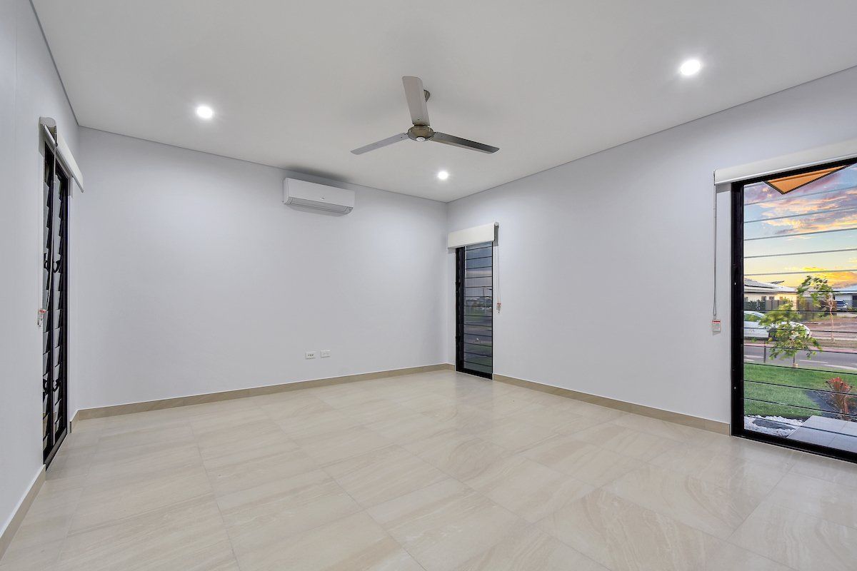 An empty room with a ceiling fan and a sliding glass door.
