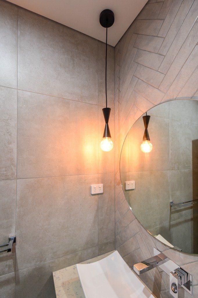 A bathroom with a sink and a round mirror.