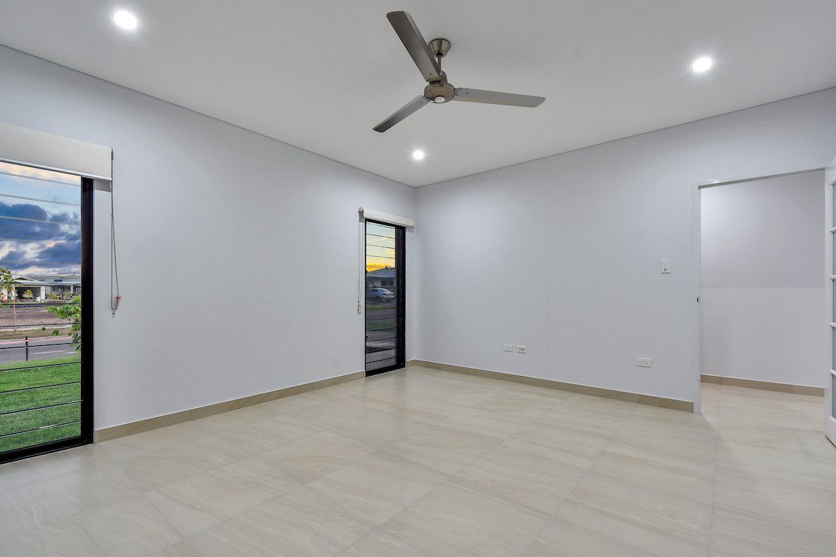An empty room with a ceiling fan and a sliding glass door.