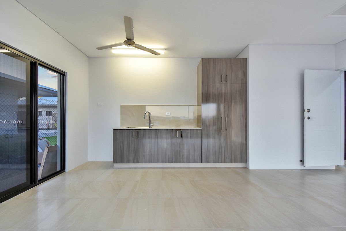 An empty room with a kitchen and a ceiling fan.