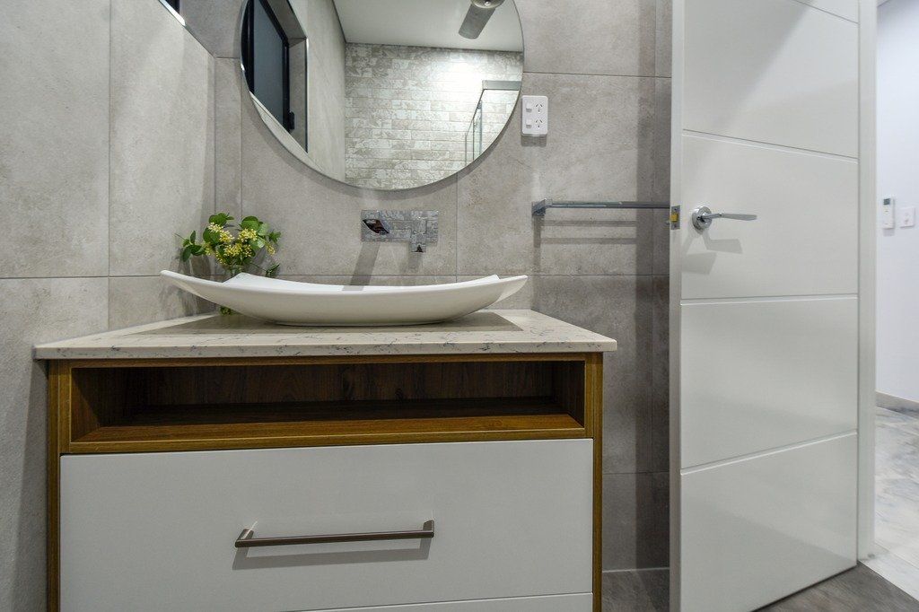 A bathroom with a sink , mirror and drawers.
