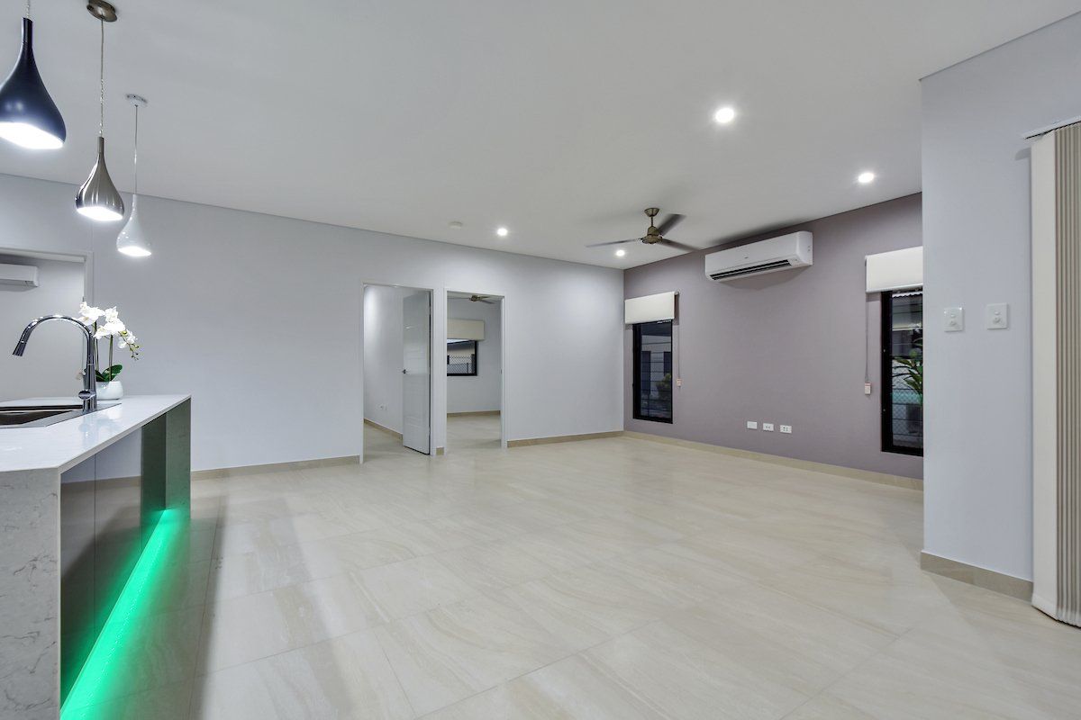 A large empty room with a ceiling fan and a green light.