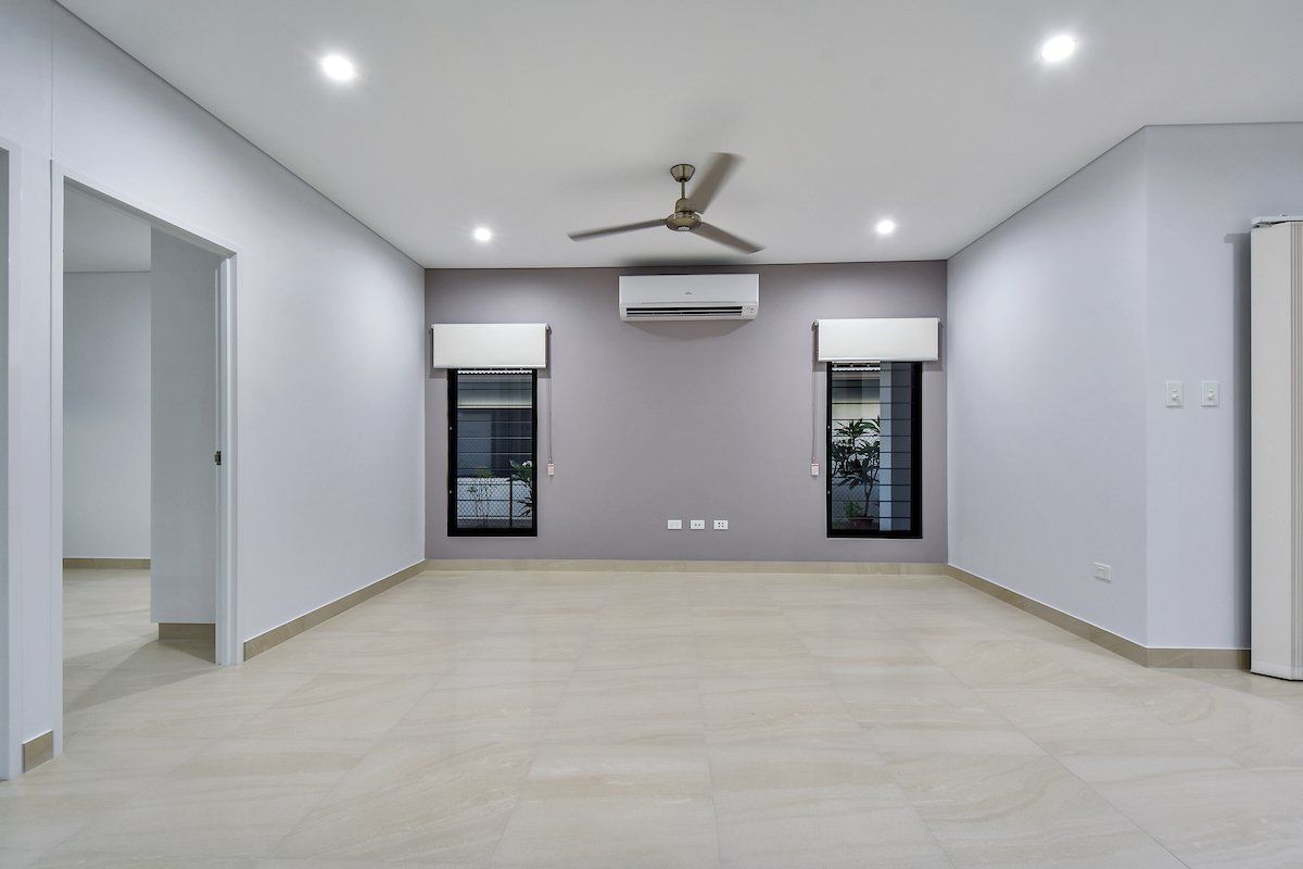 An empty room with a ceiling fan and two windows