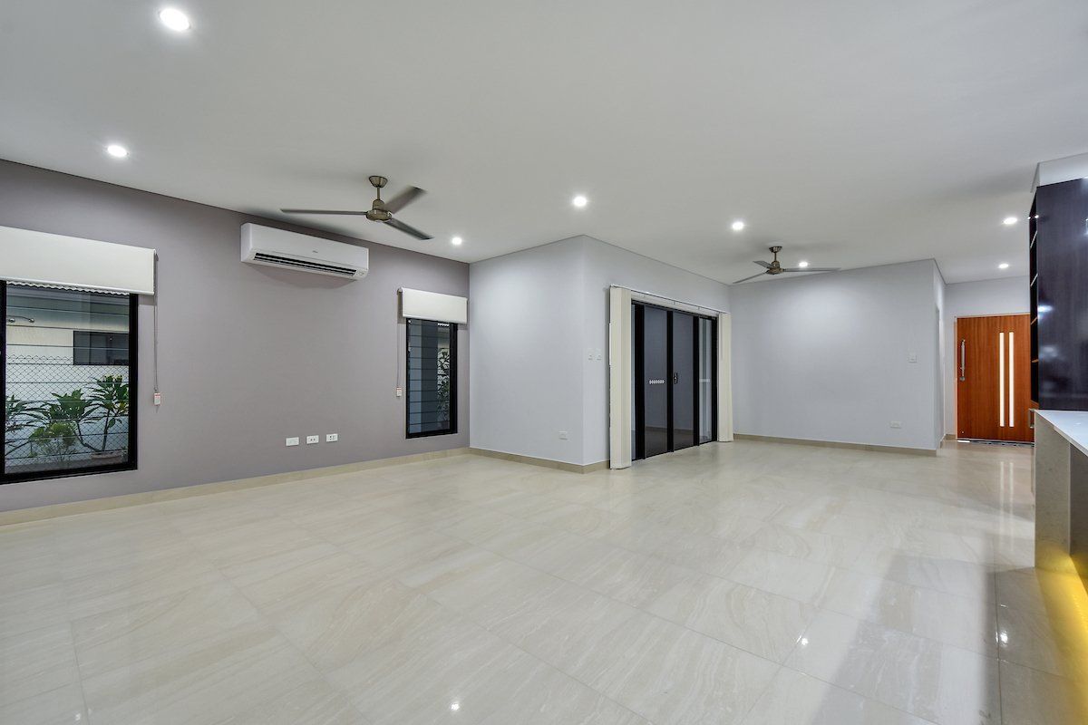 A large empty room with a ceiling fan and a lot of windows.