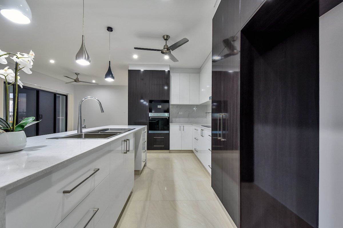 A kitchen with white cabinets and black appliances and a ceiling fan.