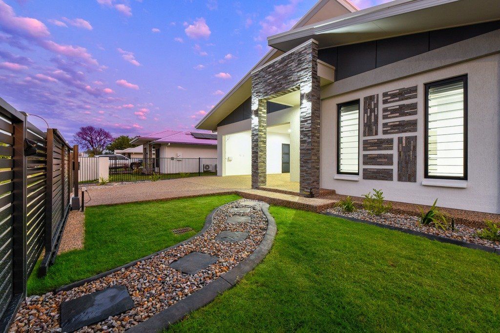 A house with a lush green lawn and a walkway leading to it.