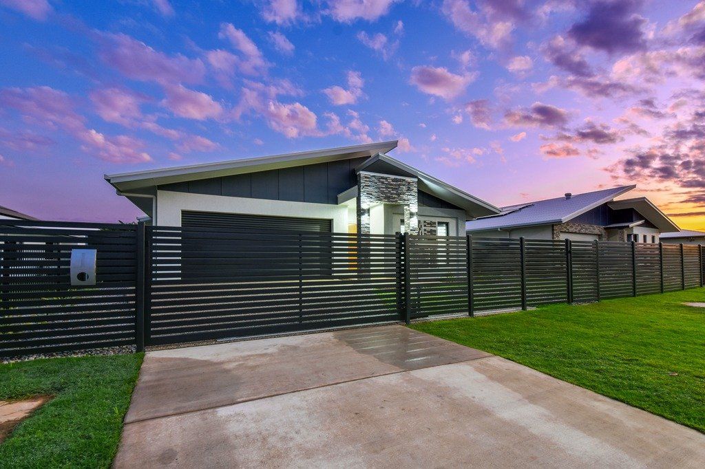 A house with a fence around it and a driveway leading to it.
