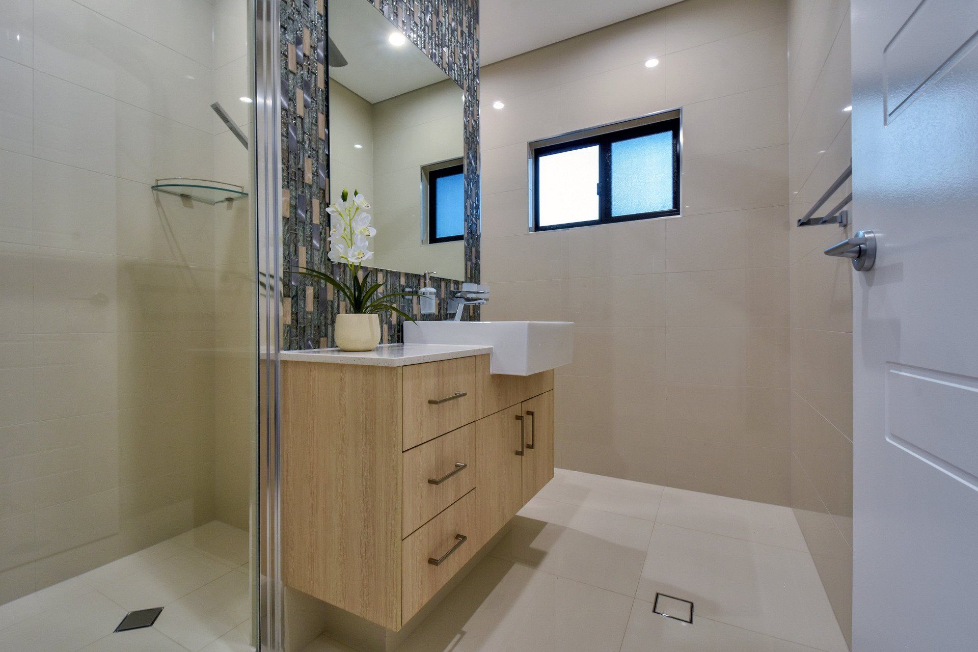 A bathroom with a sink , mirror and walk in shower.