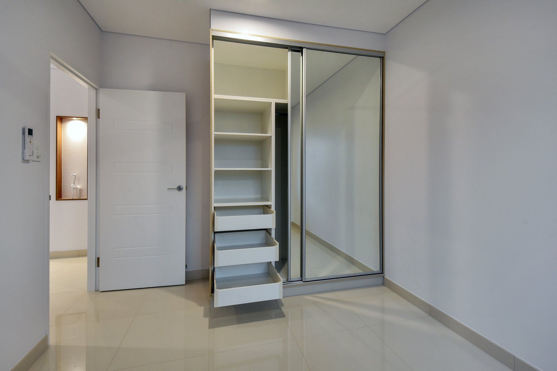 An empty room with a sliding glass door and a mirrored wardrobe.