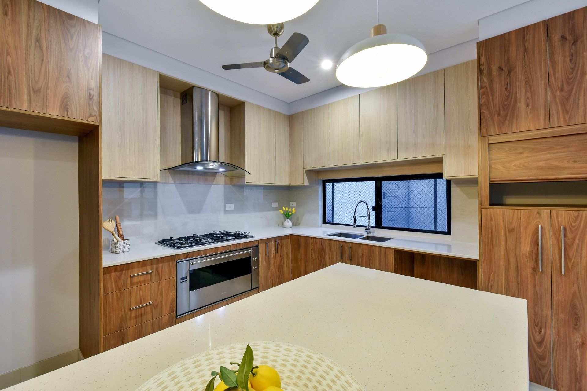 A kitchen with a ceiling fan and a bowl of lemons on the counter.