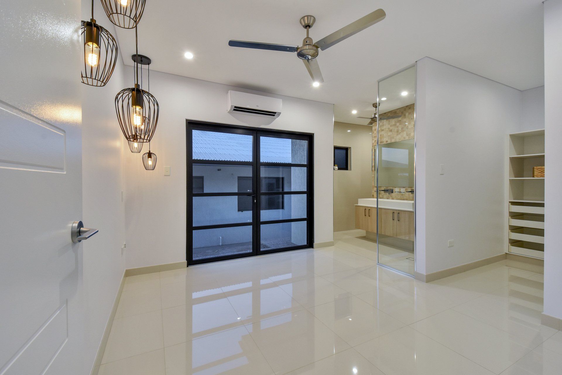 An empty room with a ceiling fan and sliding glass doors