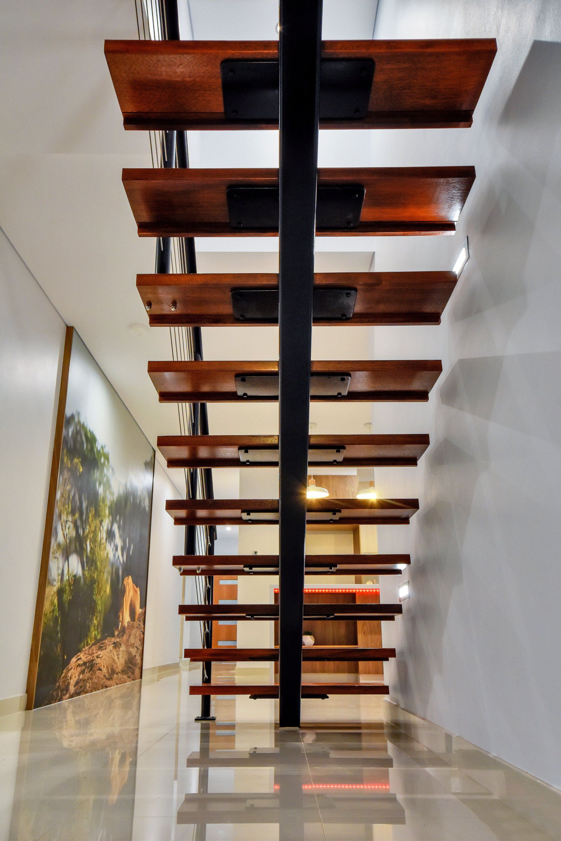 A wooden staircase in a hallway with a picture on the wall