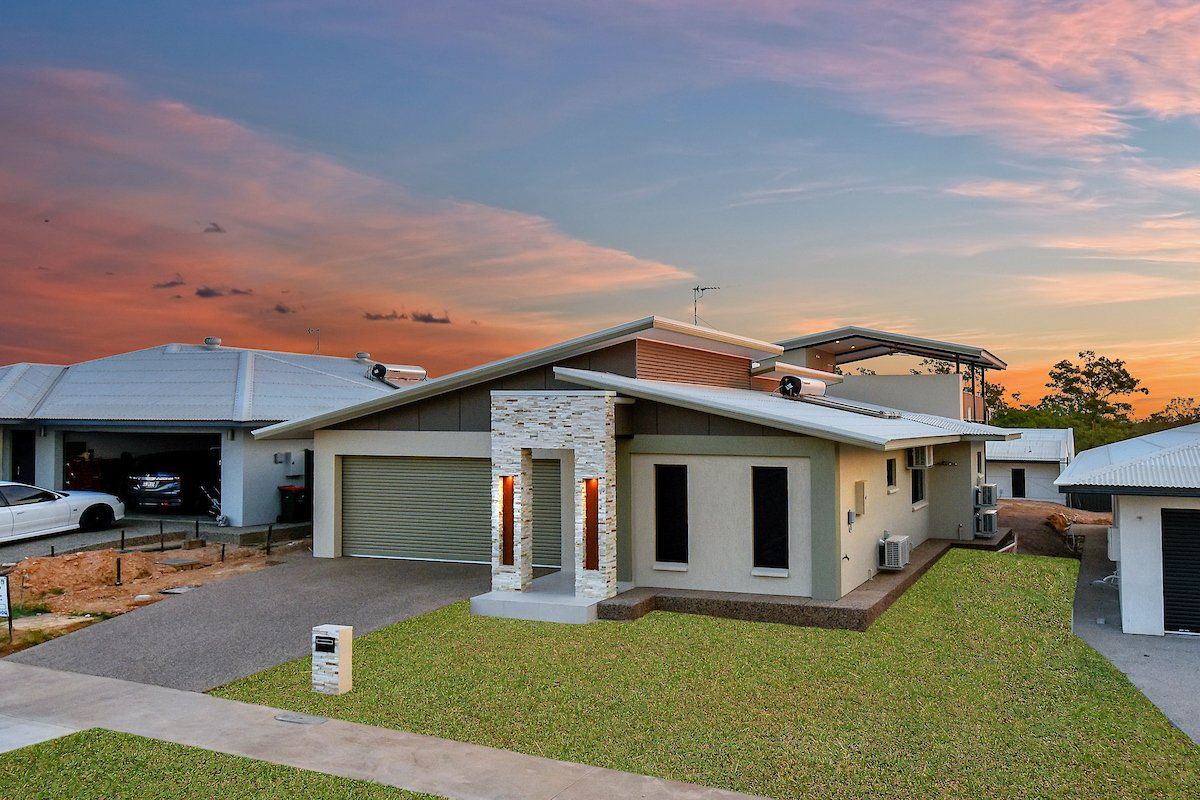 A house with a lot of grass in front of it and a sunset in the background.