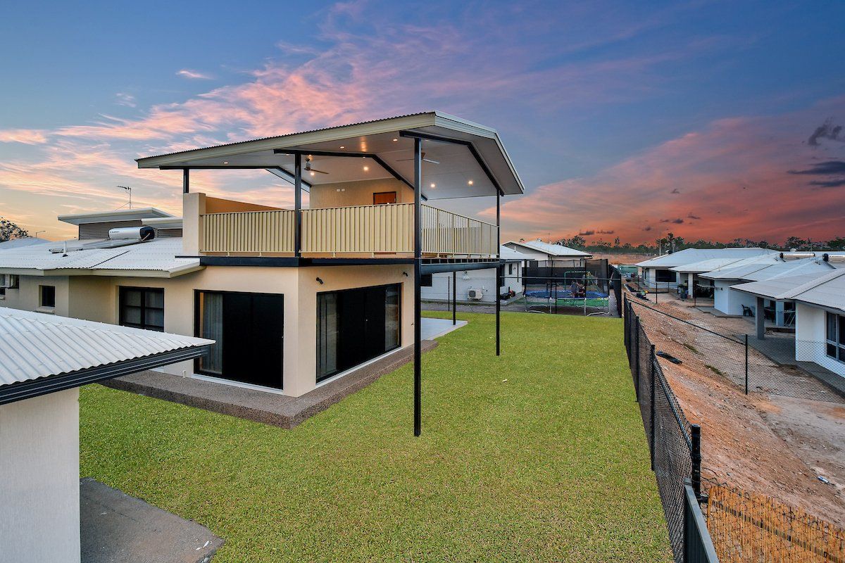 A house with a balcony and a large lawn in front of it.