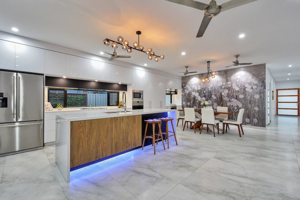A kitchen with a large island in the middle and a dining room in the background.