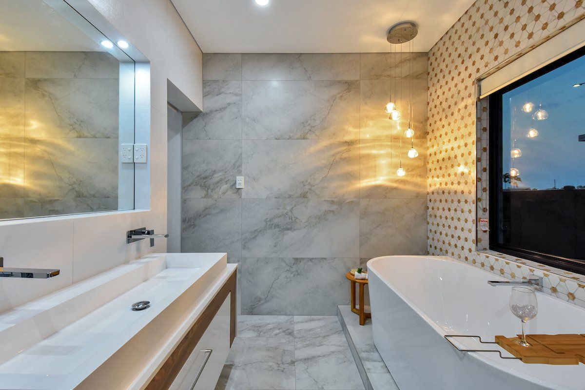 A bathroom with a tub , sink , mirror and window.