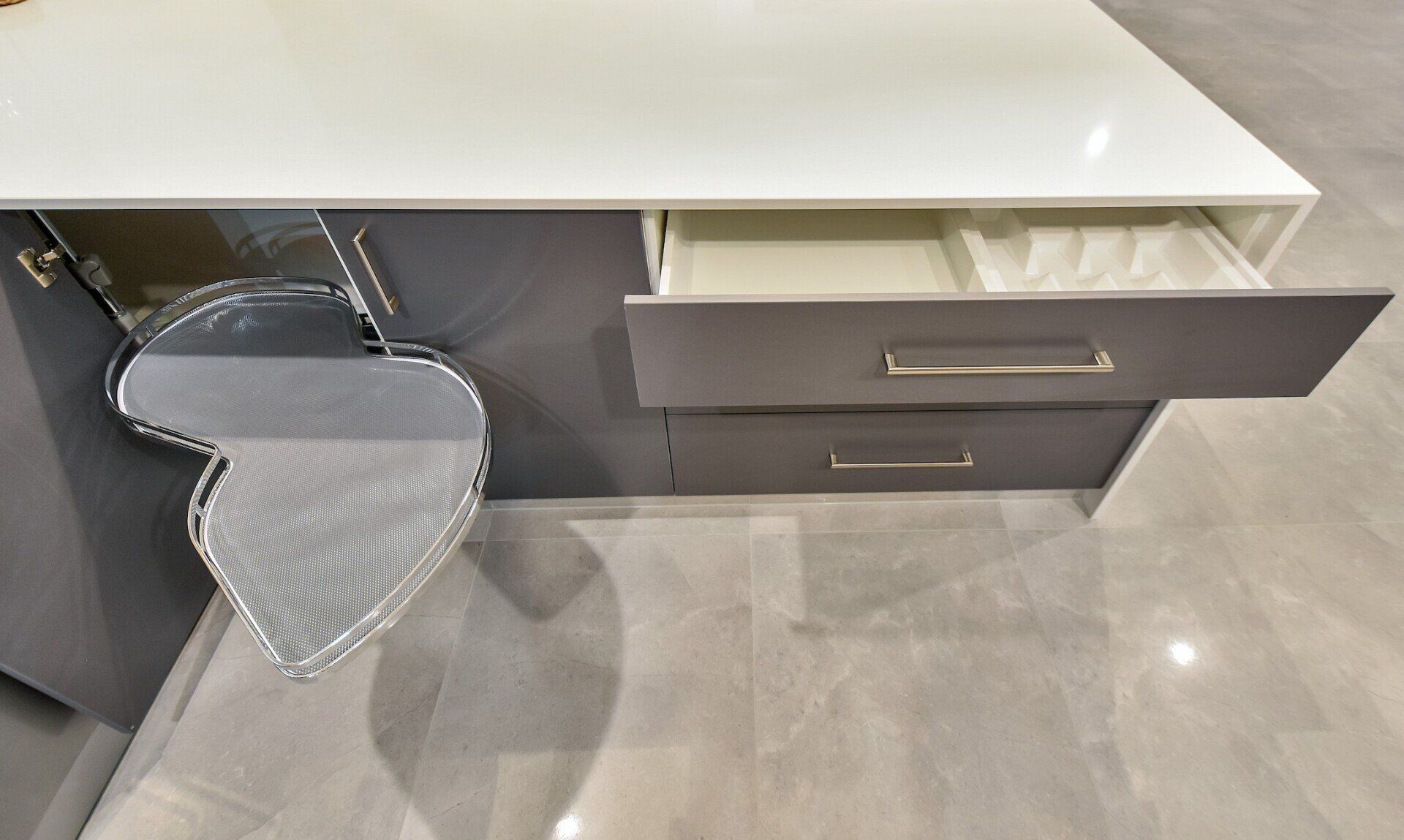 A kitchen with a white counter top and gray drawers.