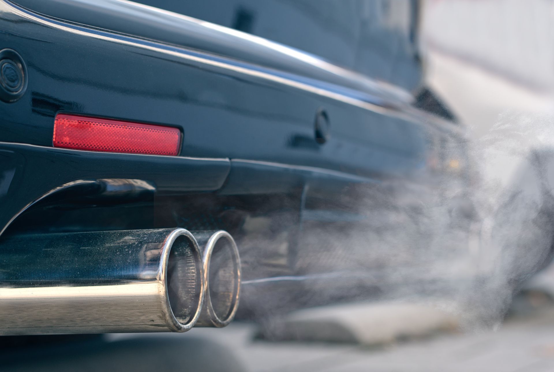 Black car exhaust billowing white smoke from dual chrome tailpipes. | Mountain Automotive and Performance