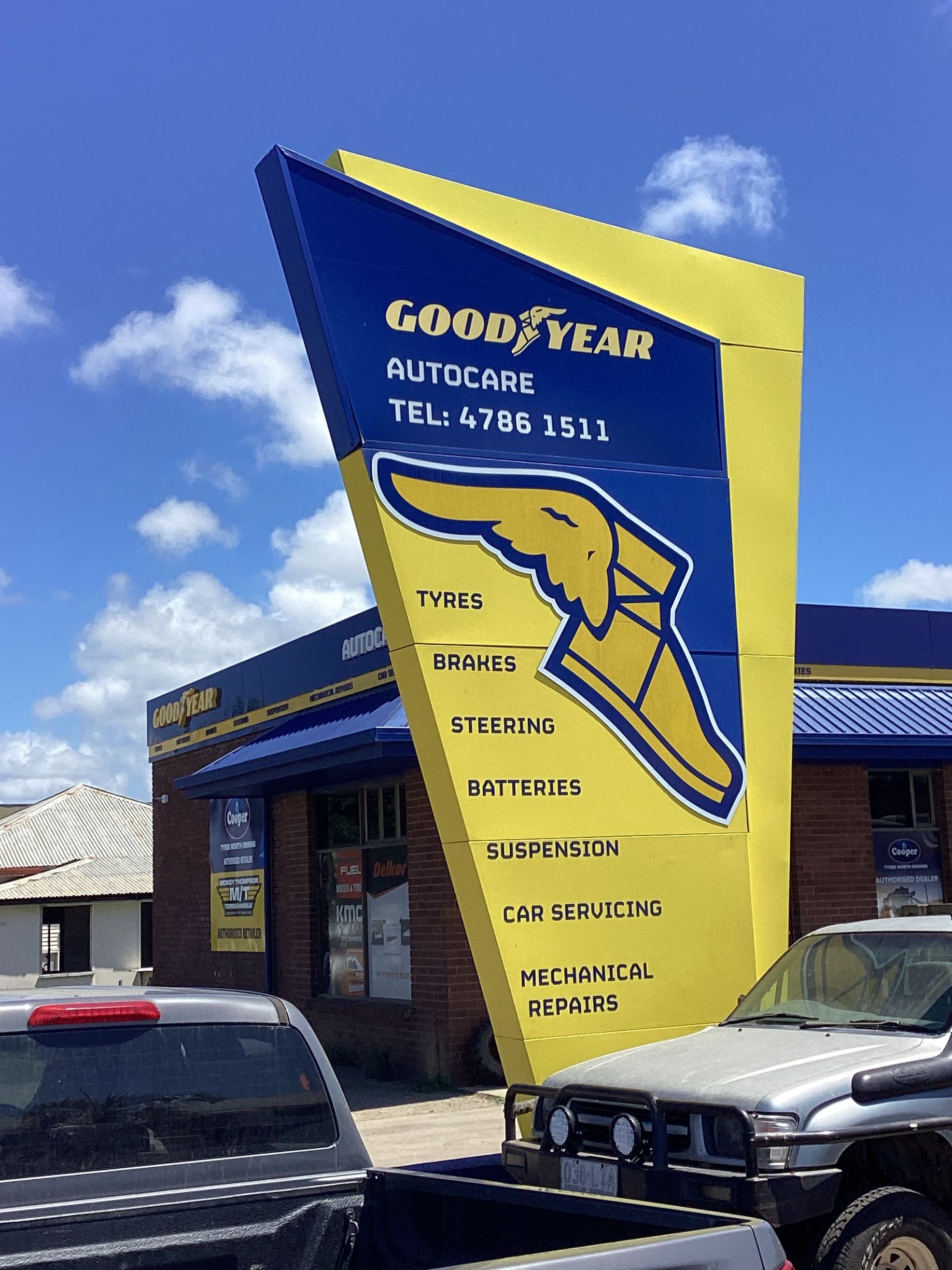 A Man Is Driving A Tow Truck Next To A White Car — Goodyear Autocare Bowen in Bowen, QLD