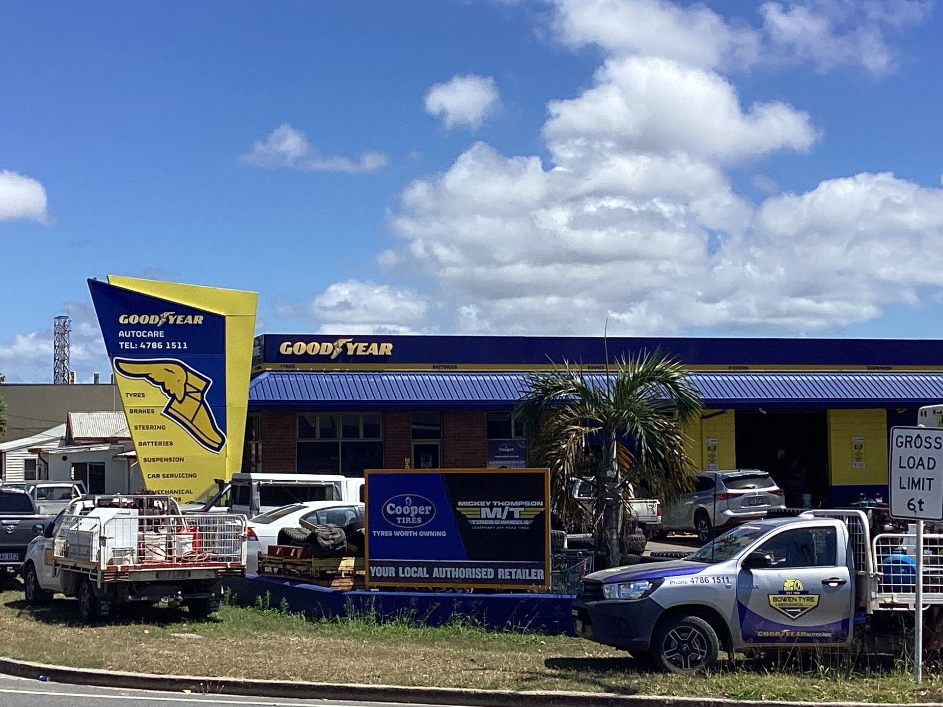A Man Is Adjusting A Tire On A Car In A Garage A Wheel Alignment Machine On A Red Car — Goodyear Autocare Bowen in Bowen, QLD
