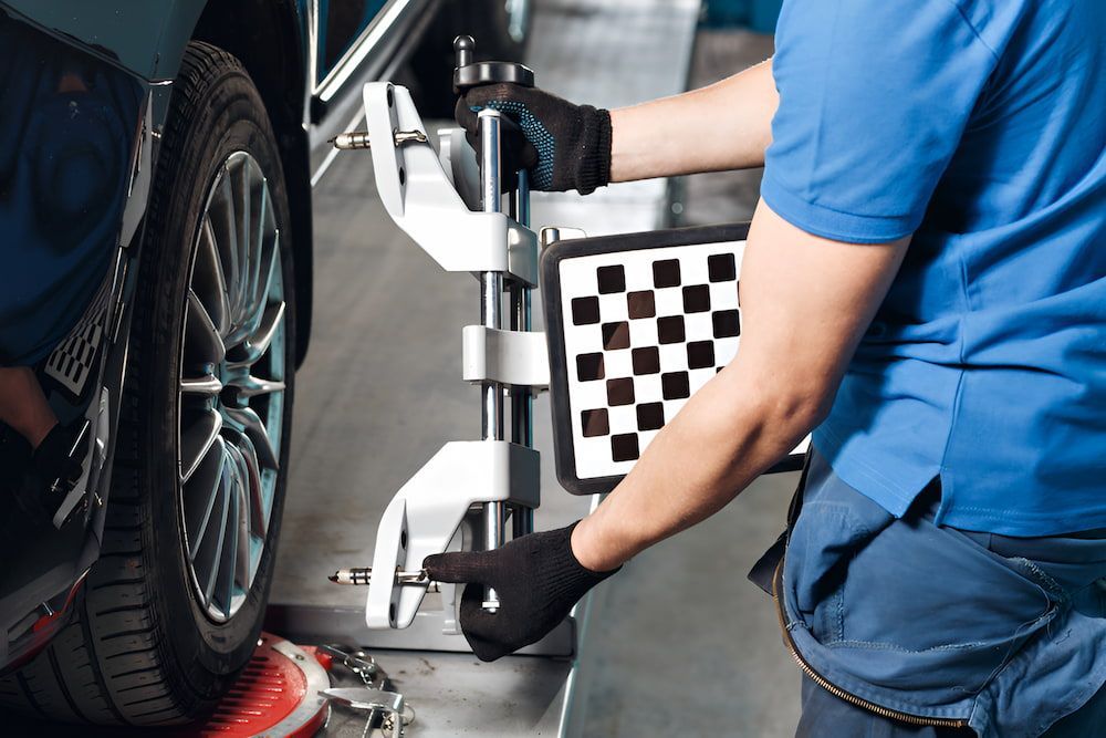 A Man Is Adjusting A Tire On A Car With A Machine — Goodyear Autocare Bowen in Bowen, QLD
