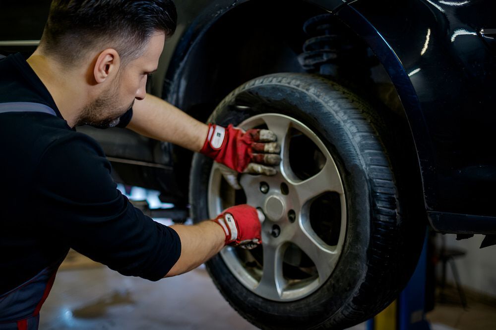 A Man Is Changing A Tire On A Car In A Garage — Goodyear Autocare Bowen in Bowen, QLD