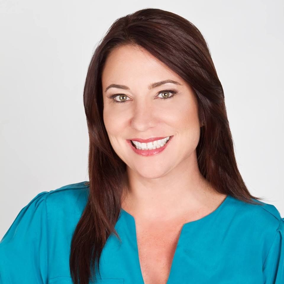 A woman in a blue shirt is smiling for the camera