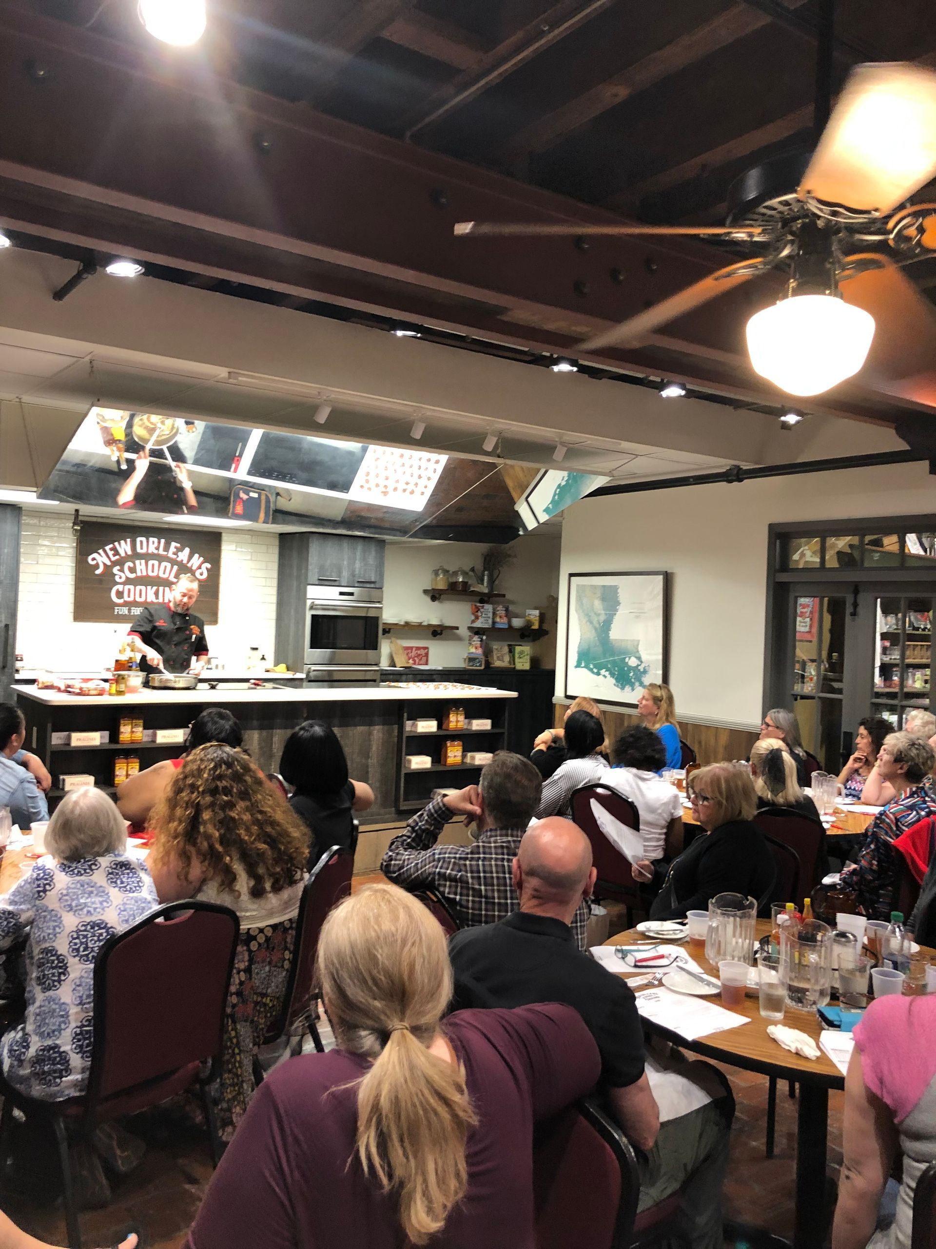 A group of people are sitting at tables in a restaurant watching a chef