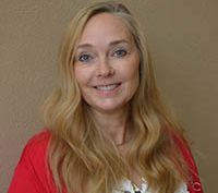 A woman with long hair is smiling in front of a balcony
