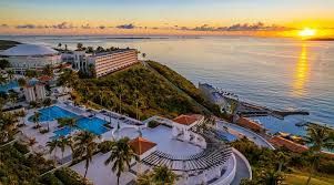 An aerial view of a resort on a hill overlooking the ocean at sunset.