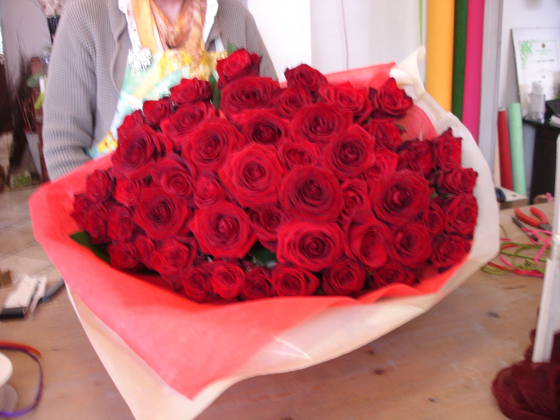 Una persona tiene in mano un mazzo di fiori su un tavolo.