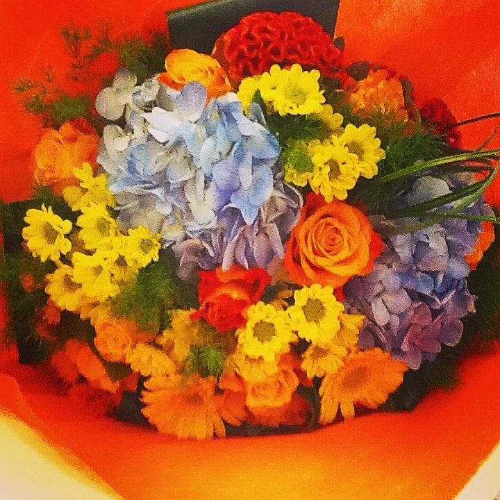 Una donna sta andando in bicicletta con un mazzo di fiori nel cestino.