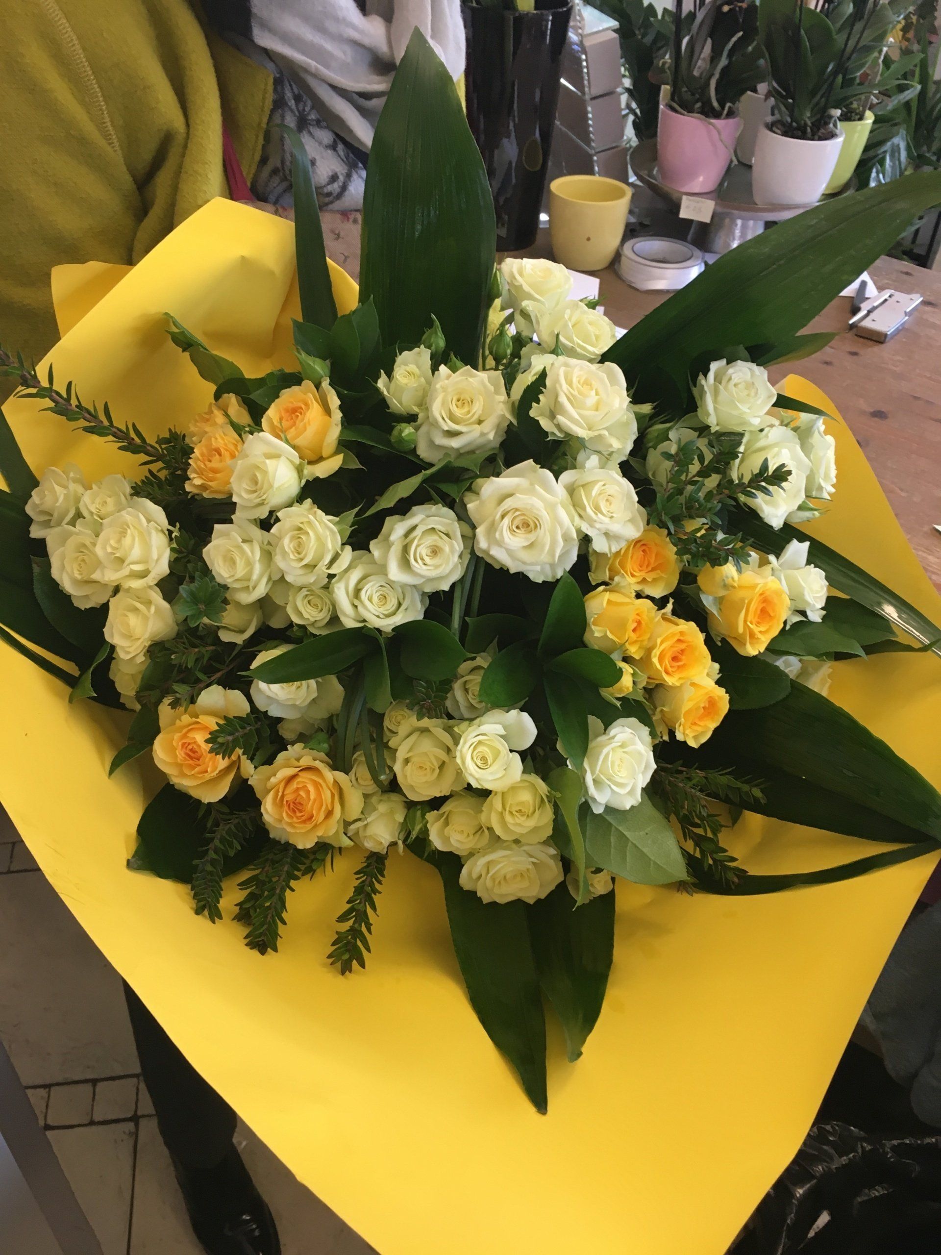 Un mazzo di rose gialle e bianche avvolto in carta gialla