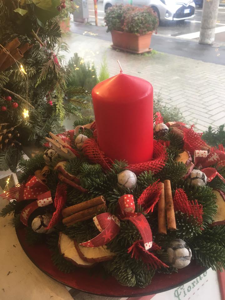 Una corona di Natale con una candela rossa al centro