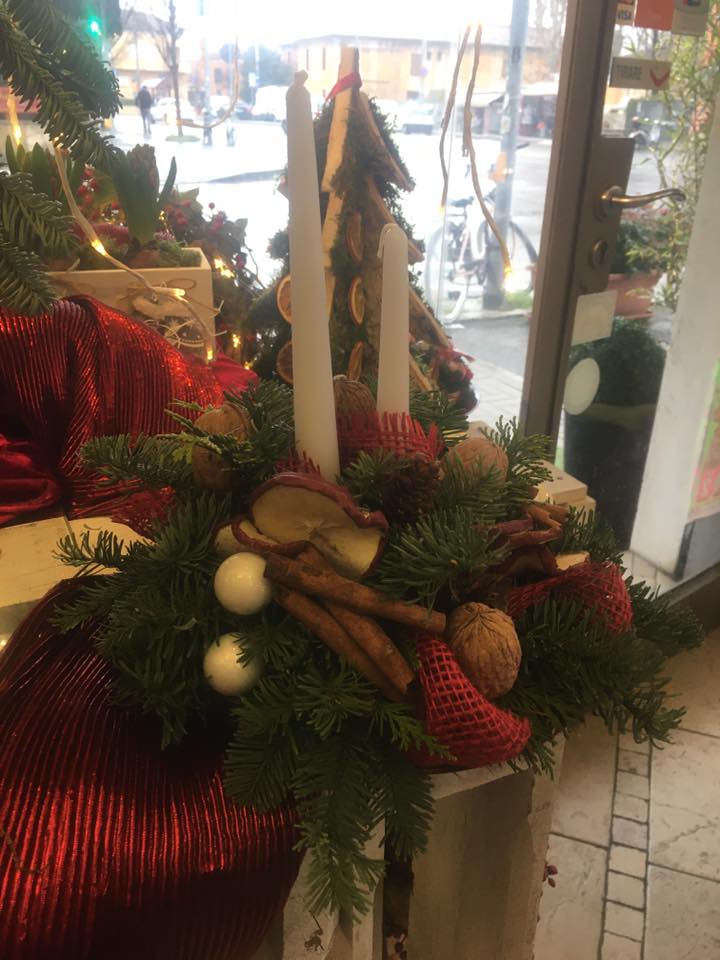 Una composizione natalizia con candele, noci, pigne e un albero di Natale in una finestra.
