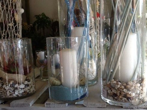 Un mazzo di vasi con candele e conchiglie al loro interno