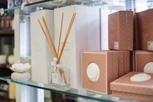 Uno scaffale con sopra una bottiglia di diffusori di profumo a bastoncini e delle scatole.