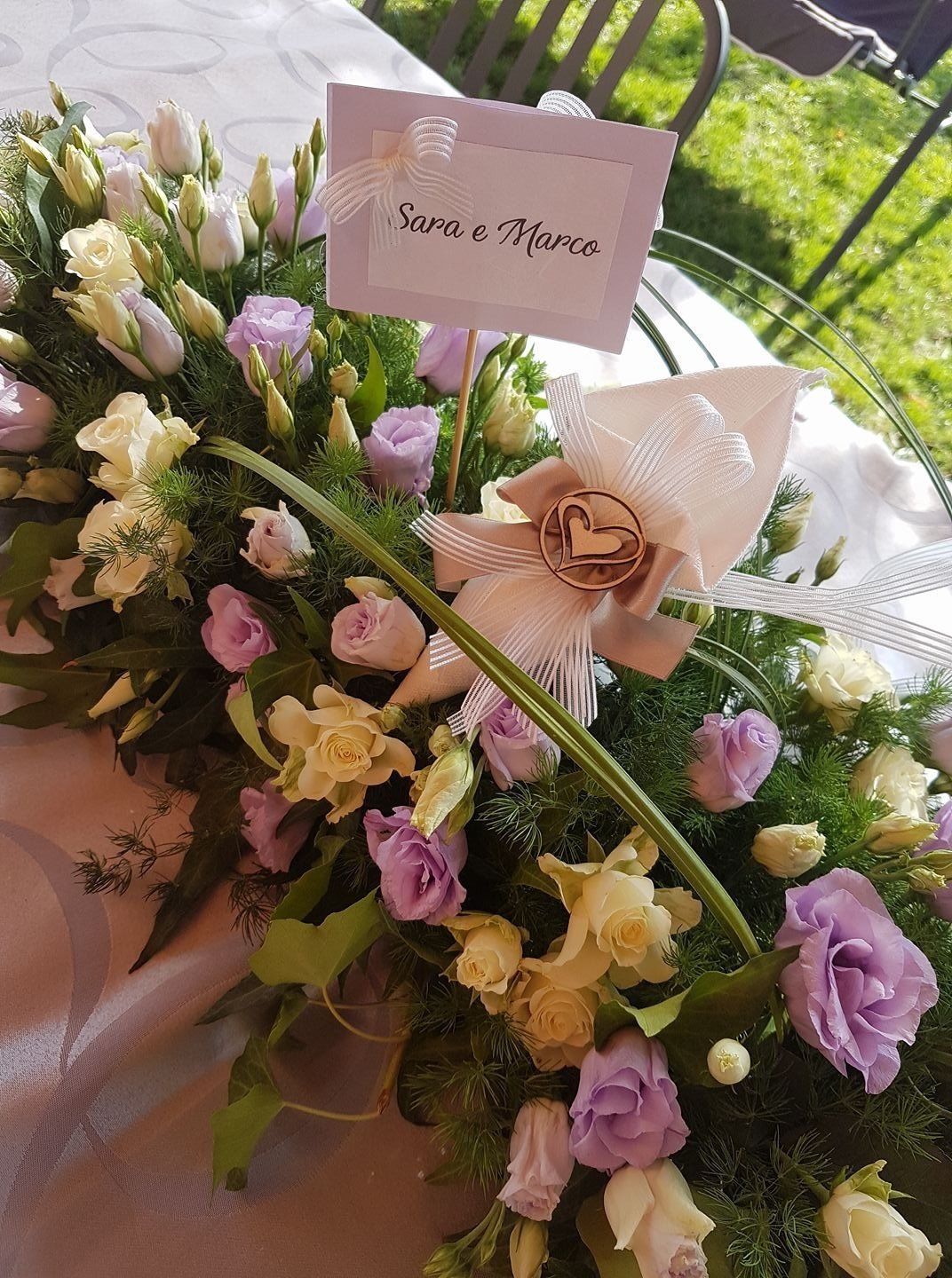 Una persona tiene in mano un mazzo di fiori rosa e bianchi.