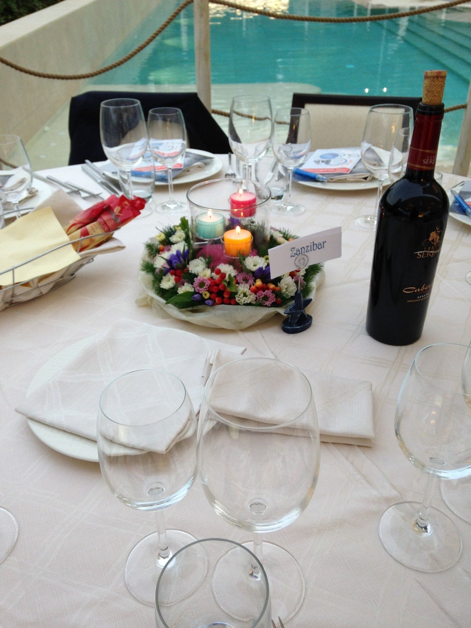 Una bottiglia di vino è appoggiata su un tavolo accanto a una composizione floreale