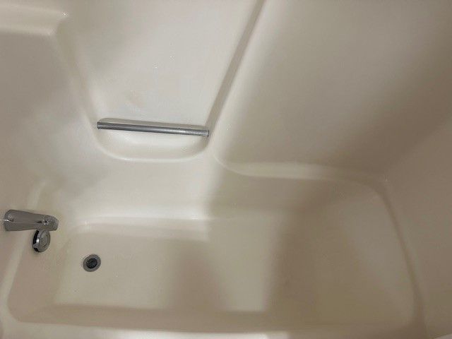 a white bathtub with a chrome faucet and railing . | Erie, PA | Peterson's Property Maintenance