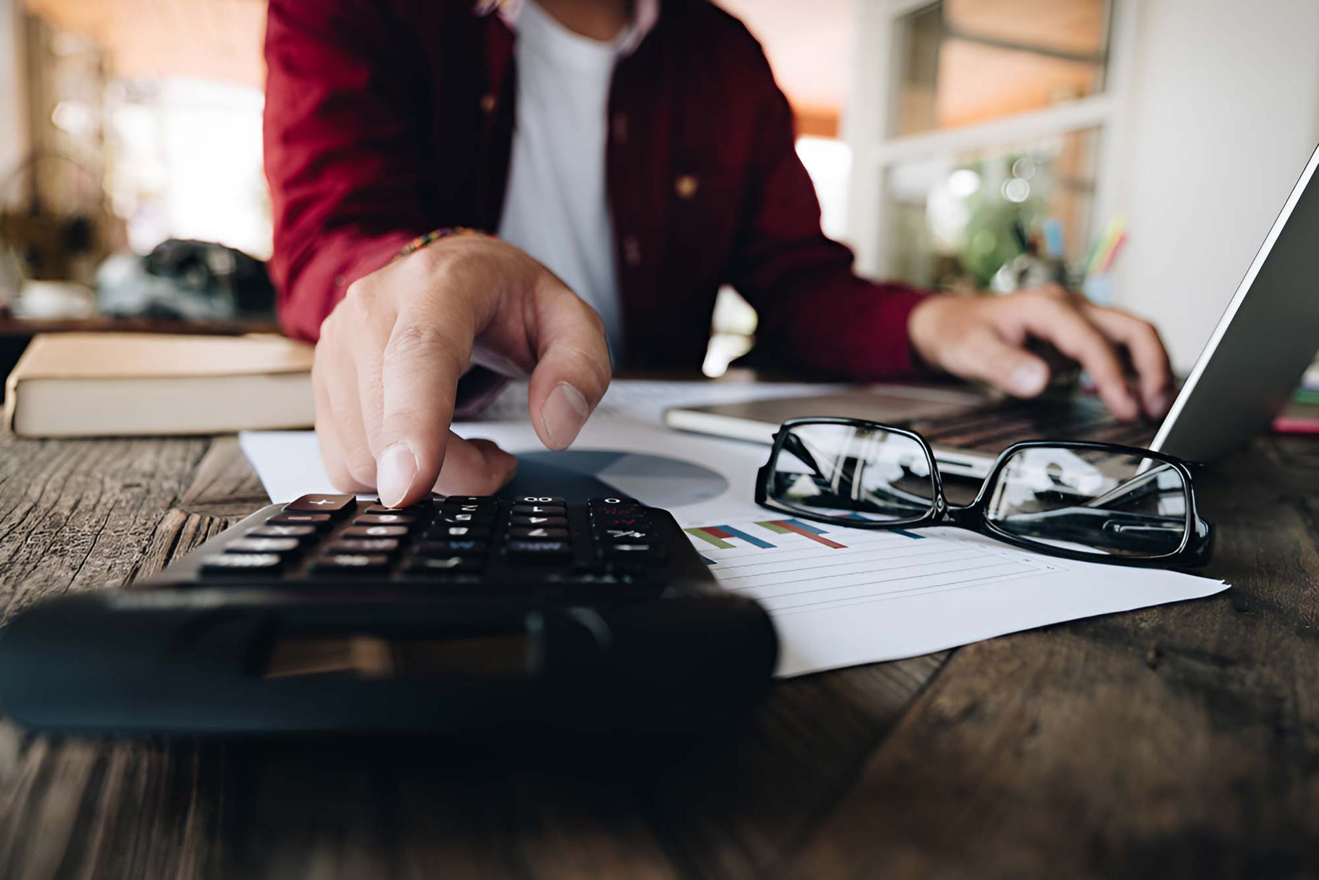A Man Is Using A Laptop And A Calculator At The Same Time — Whitson Dawson Accountants in Central Queensland