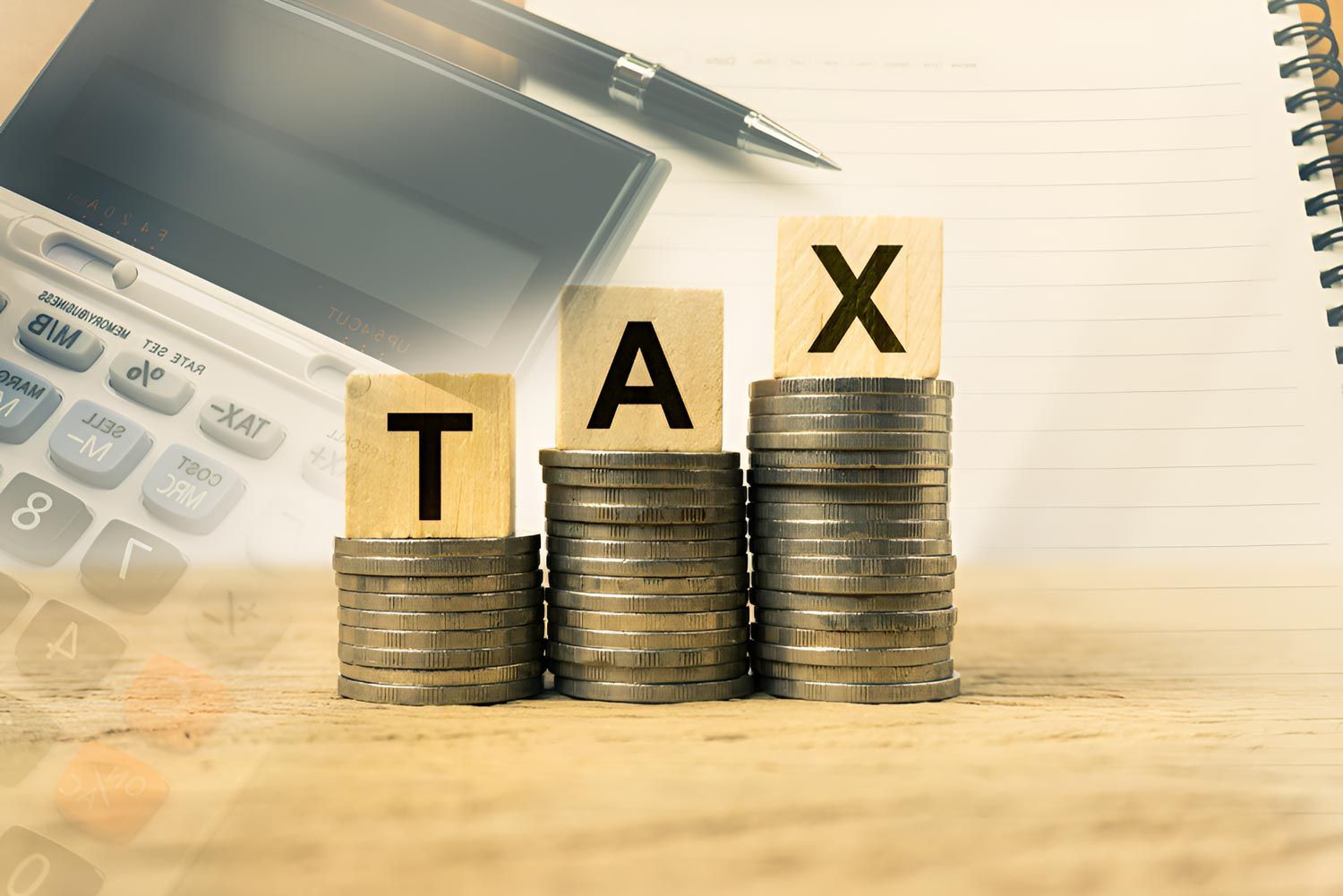 The Word Tax Is Written On Wooden Blocks On Top Of Stacks Of Coins — Whitson Dawson Accountants in Mackay, QLD