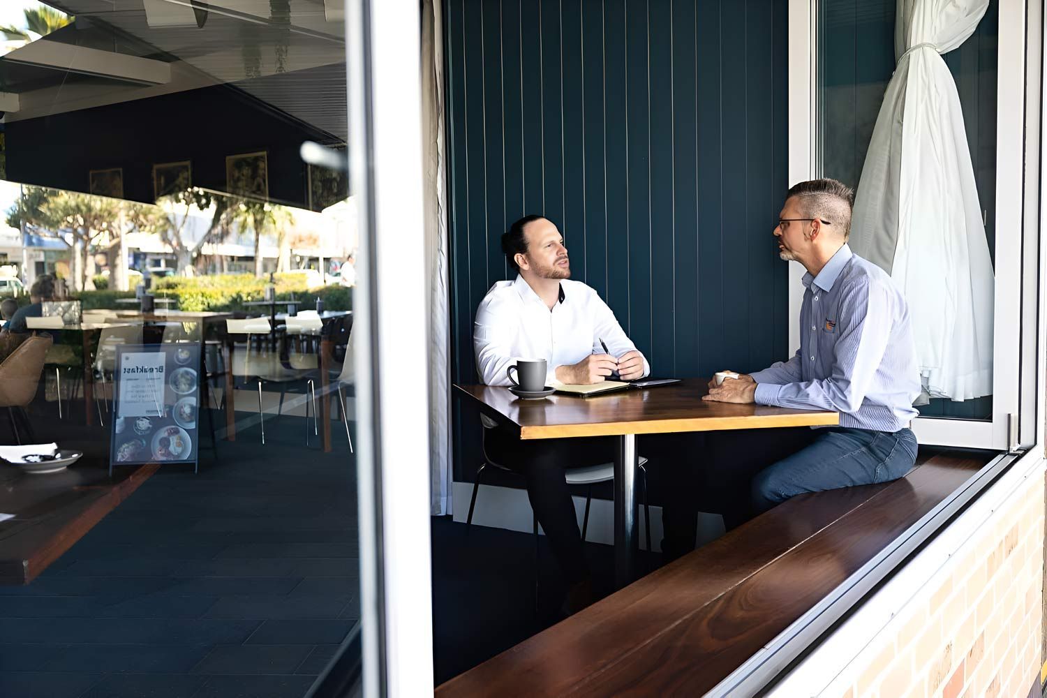 Two Accountant Men Are Seated At A Table Near A Window — Whitson Dawson Accountants in Central Queensland