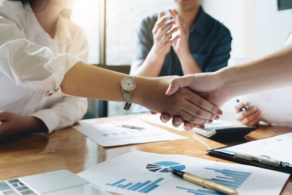 Two People Shaking Hands With Papers And A Pen Doing Taxes