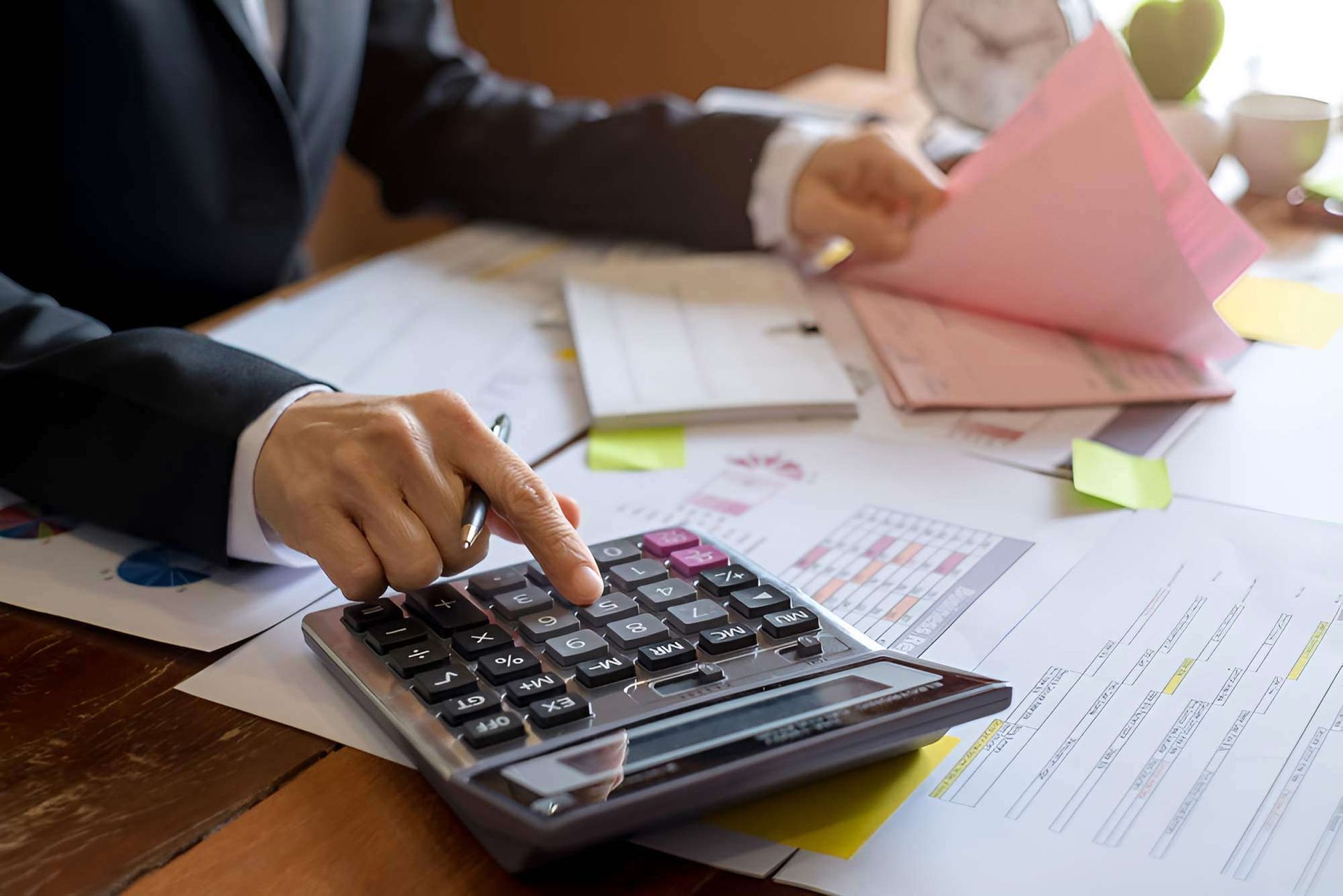 A Man In A Suit Is Sitting At A Desk, Using A Calculator — Whitson Dawson Accountants in North Queensland