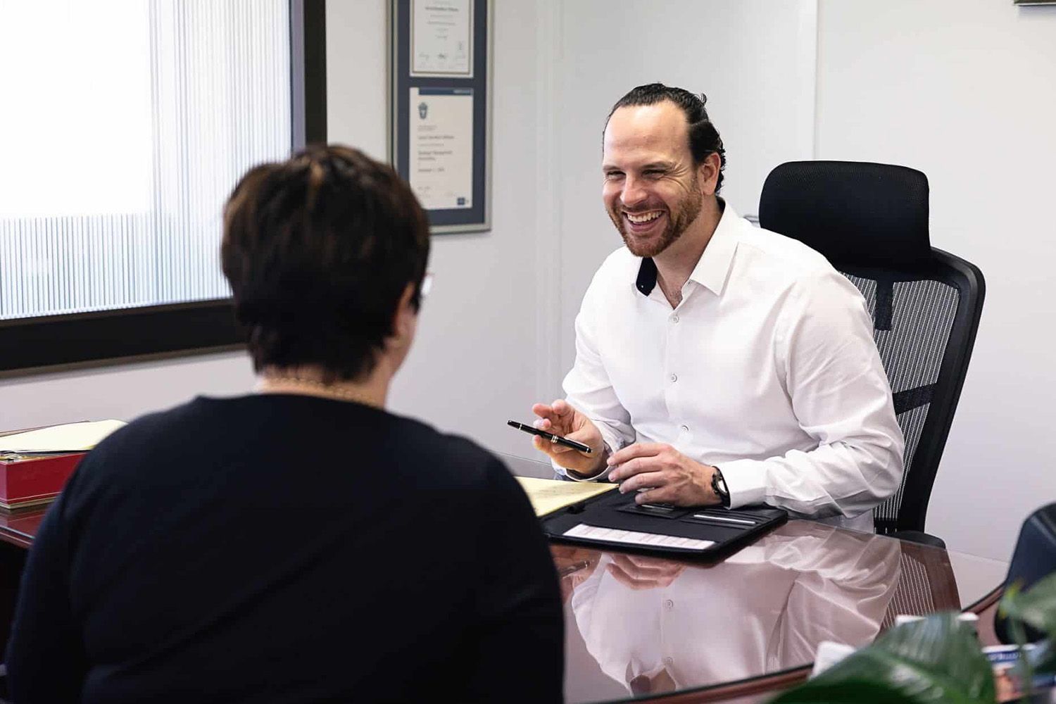 Man in White Polo Reviews Documents with a Person in a Meeting Setting
