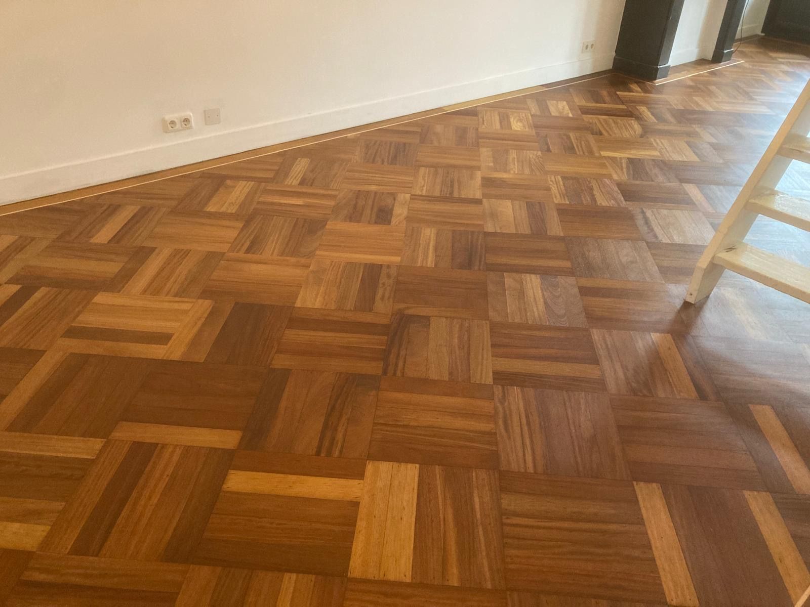 Een houten vloer met een visgraatmotief in een kamer met een ladder.