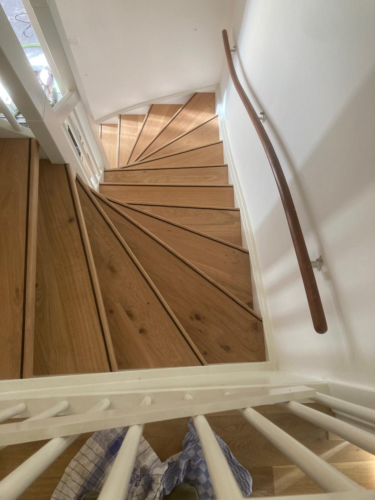 De trap is van hout en heeft een witte leuning.