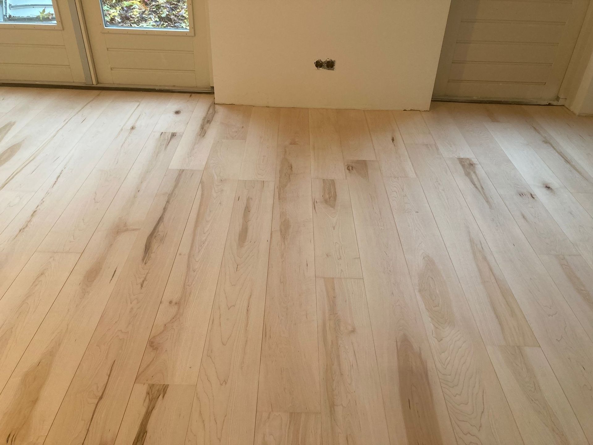 Een kamer met een houten vloer en een witte muur