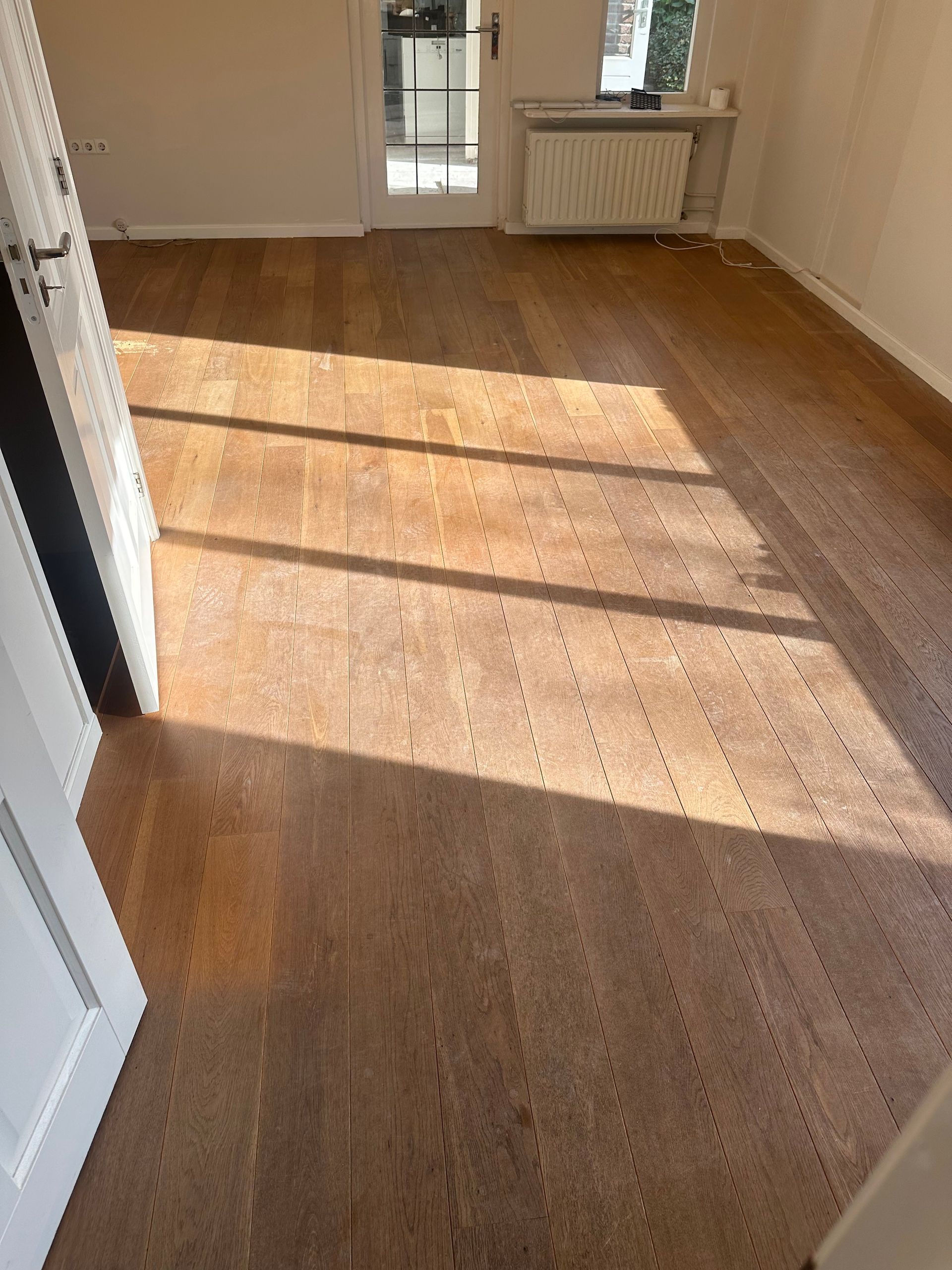 Een kamer met een houten vloer en een witte deur.